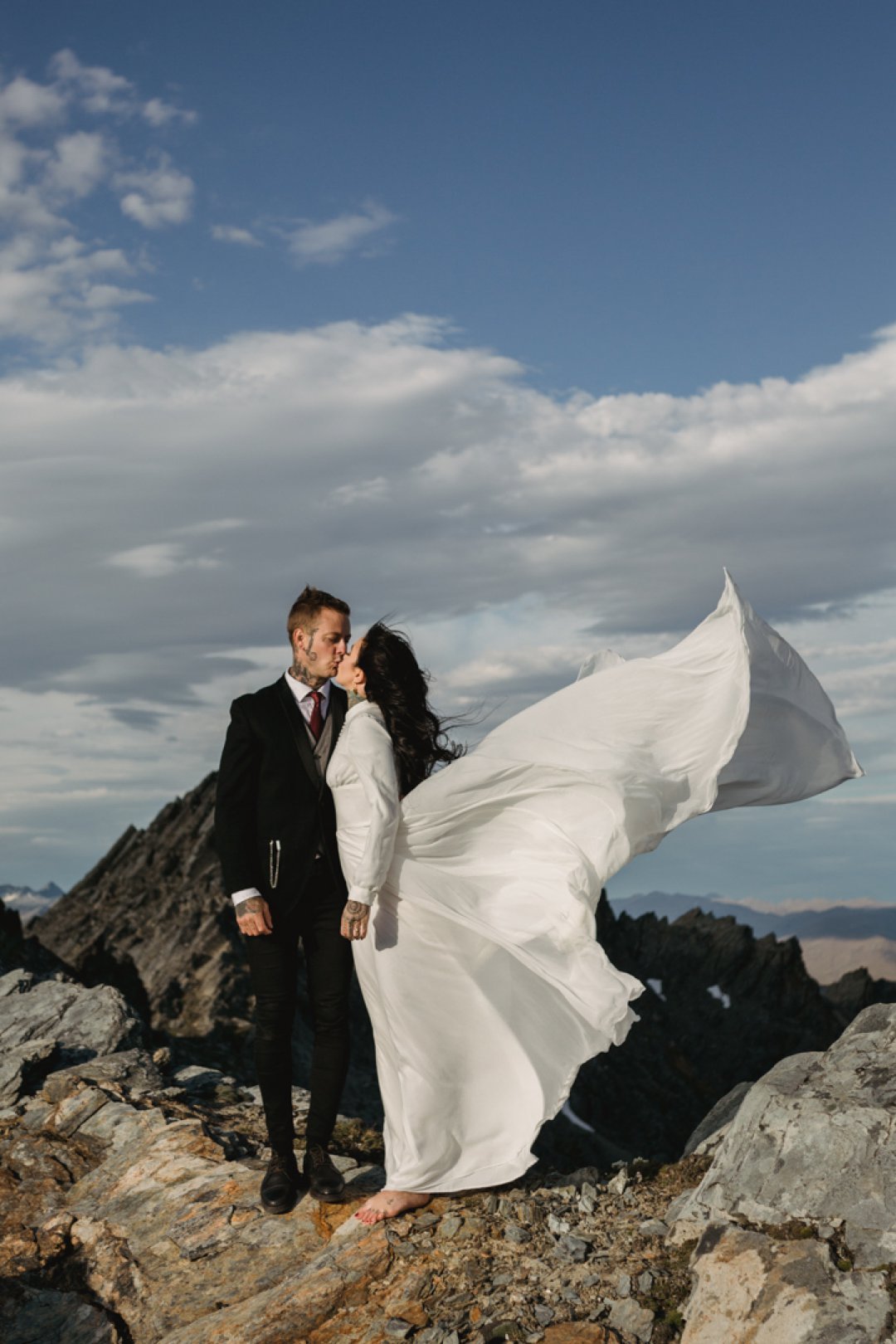 New Zealand bride wearing a long white flowing gown on mountain top wedding ceremony in New Zealand by Dawn Thomson Photography