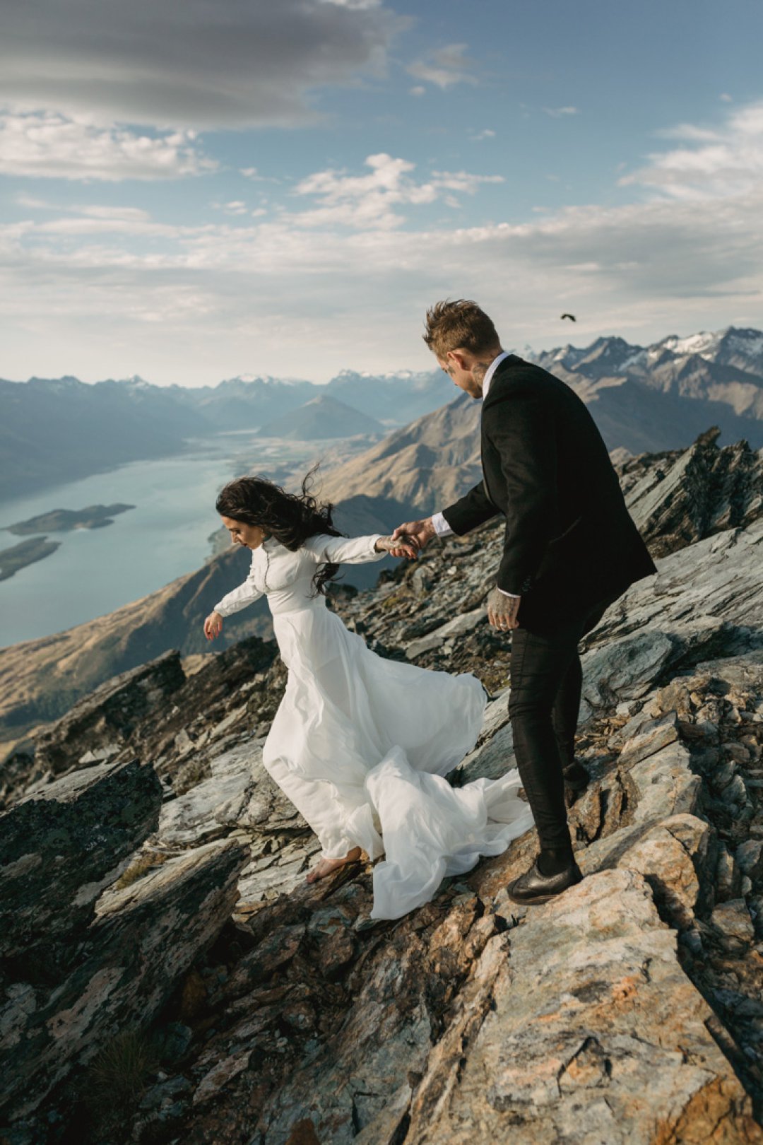 Bride and groom holding hands and standing on mountain top for their helicopter wedding in New Zealand by Dawn Thomson Photography