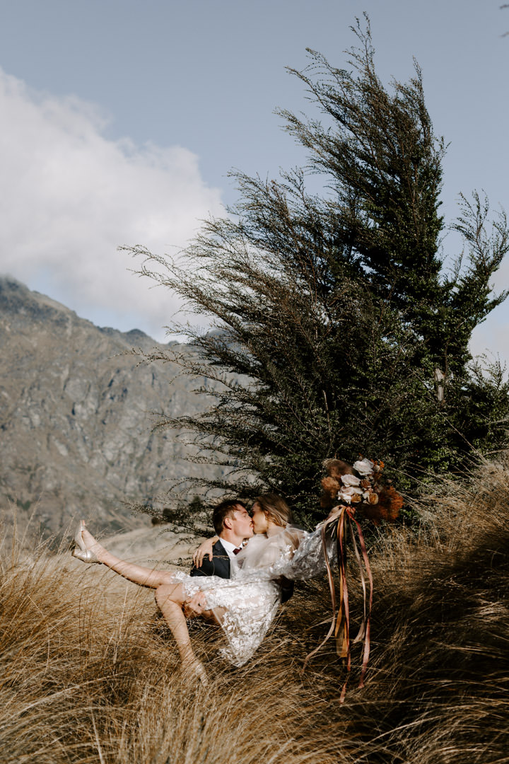 Bride and groom kissing in tussocks at Jacks Retreat Elopement Wedding in Queenstown, New Zealand by Dawn Thomson Photography