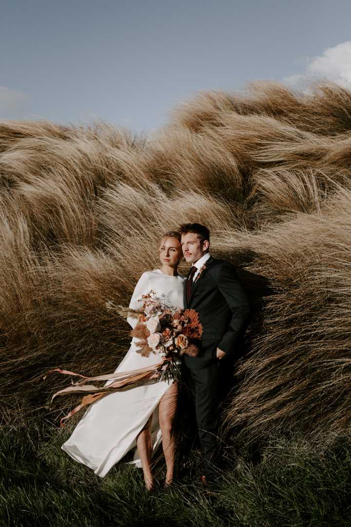 Bride and groom in tussock grass at Jacks Retreat Elopement Wedding in Queenstown, New Zealand by Dawn Thomson Photography