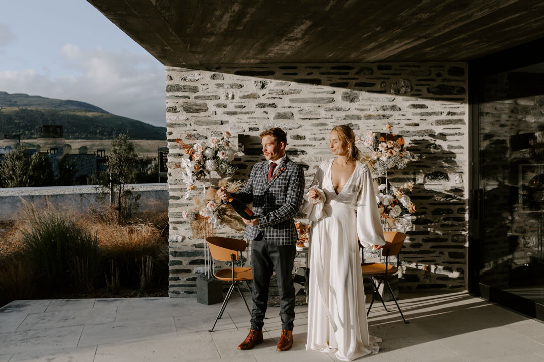 Bride and groom popping champagne at Jacks Retreat Elopement Wedding in Queenstown, New Zealand by Dawn Thomson Photography